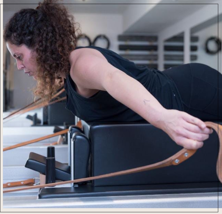 מתאמנת עושה תרגלי אימון על מיטת פילאטיס מכשירים בסטודיו