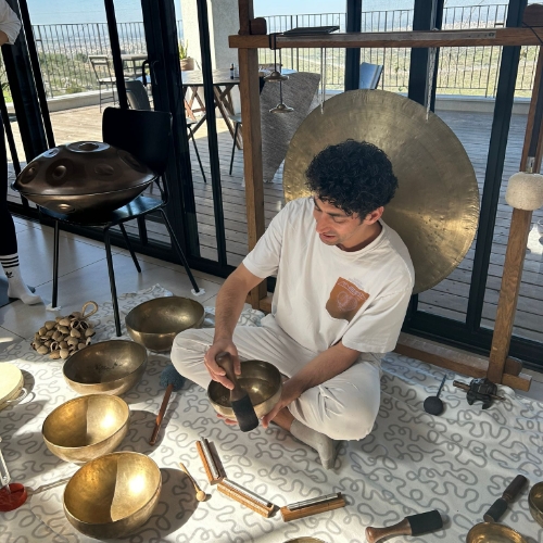 סדנאת הילינג מעוברת בסלון אשר בתמונה מדריך ההילניג יושב על מזרן ומעביר סדנא