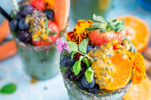 תמונה של שתי כוסות מיץ אשר בשניהם יש כמות גדולה של פירות כמו תפוז תות אוכמניות דובדבן נענע