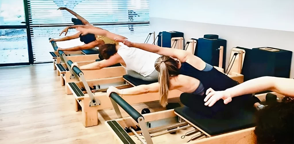 קבוצת נשים עושות מתחיות על מיטת פילאטיס מכשירים