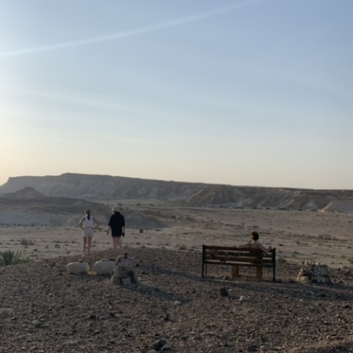 קבוצה של מטיילות אשר מטיילת עכשיו יושבת ושתיין עומדות מול נוף הרים בטבע